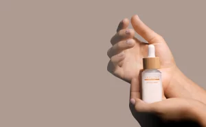 Hände halten eine Flasche mit einem Hautpflegeprodukt von NEAUTHY mit Pipette und Holzverschluss.